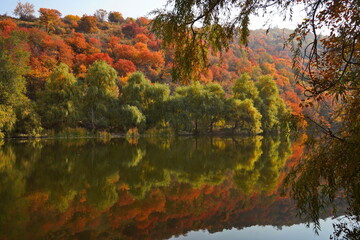 Soldier Lake. A lake in a mountainous area with different vegetation. Bright juicy autumn leaves, leaf fall and reflection in the water.