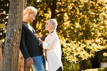 Fototapeta premium Young couple sharing a tender moment under sunny trees in a blissful outdoor setting