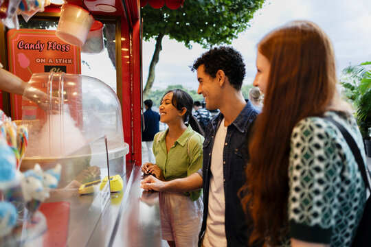Friends buying cotton candy at outdoor funfair food stand
