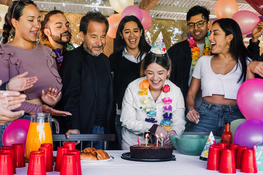 portrait of latin family celebrating in birthday party at terrace outdoors in Mexico Latin America. Hispanic group of people multi age and multicultural eating cake and holding gifts - Powered by Adobe