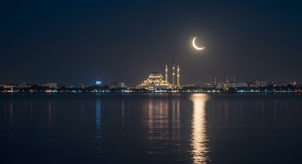 Fototapeta premium Crescent Moon over Illuminated Mosque and City Skyline Reflected in Water at Night