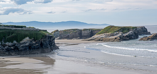 Rocks in the sea with a mountain in the background