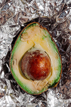 Expired avocado half with seed on foil close-up