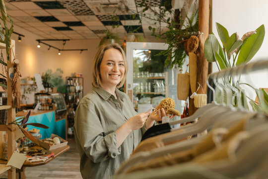 Smiling woman holding bath sponge in organic store