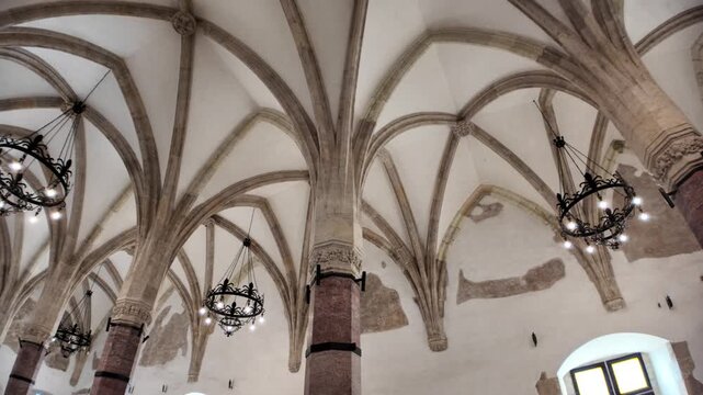 Corvin Castle's interior showcasing the vast great hall with multiple octagonal columns, impressive vaulted ceilings, and remnants of old frescoes on ancient walls in Hunedoara, Romania Transylvania