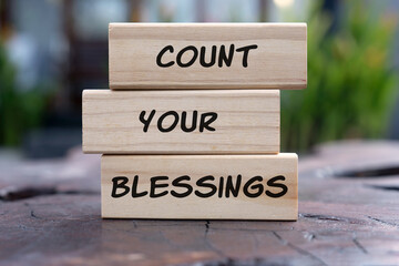 Three stacked wooden blocks with the inspirational quote "Count Your Blessings." Focus on gratitude, positivity, mindfulness, and appreciation. Concept image for happiness and well-being.