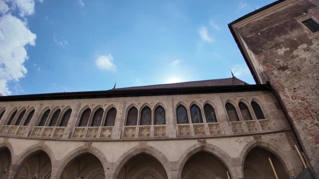 Corvin Castle in Hunedoara: imposing Gothic-Renaissance fortress with stone steps, arches and layered courtyards under a vivid blue sky, showcasing medieval Romanian heritage of Transylvania