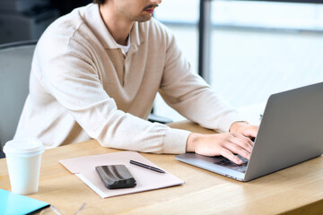 Handsome young man focused on work at a modern desk in a bright office setting