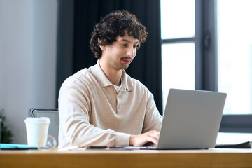 Handsome young man working on laptop in a bright and modern office space