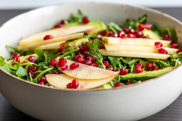fall salad with arugula apple pomegranate and caramelized pecans close up