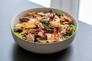 fall salad with arugula apple pomegranate and caramelized pecans close up