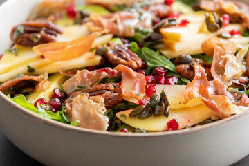fall salad with arugula apple pomegranate and caramelized pecans close up