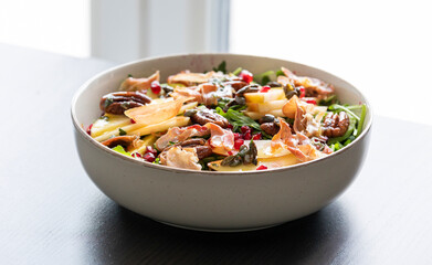 fall salad with arugula apple pomegranate and caramelized pecans close up