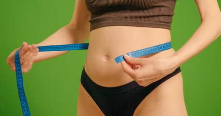 Pregnant woman measuring her belly against green screen background. Early pregnancy video shot...