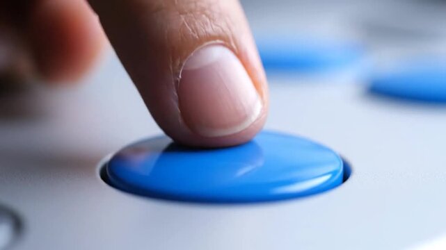 Close-up of a finger pressing a bright blue, glossy button on a light-colored control panel