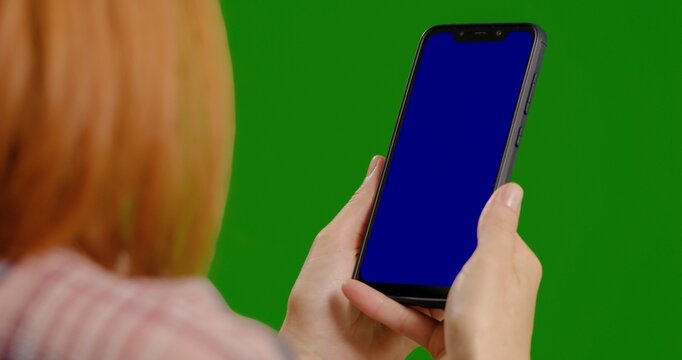 Close up shot of woman studying on blue mock up screen on green screen background. Female watching phone vertically. - Powered by Adobe