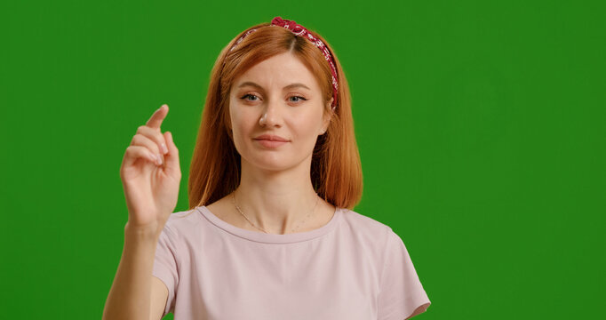 Beautiful young woman using interactive touch screen with various gestures isolated green screen background. Casual woman using touch screen moving fingers.