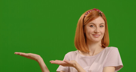 Happy woman face shows flat palms at commercial promotion or advertising copy space or marketing mockup over green screen background. Portrait, product placement female on chroma key model.