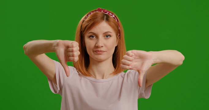 Woman, thumbs down and face by green screen for disagree, review and bad news by background, emoji and negative with hand sign for announcement. - Powered by Adobe