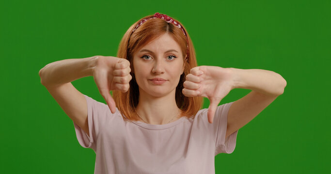 Woman, thumbs down by green screen for disagree, review and bad news by background, emoji and negative with hand sign for announcement.
