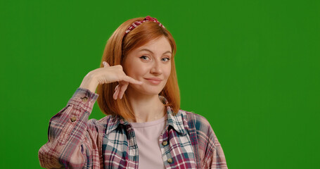 Call me, gesture and face of Asian woman on a green screen isolated on a studio background. Phone, trendy and a portrait of happy, edgy and young girl gesturing for calling on a mockup backdrop