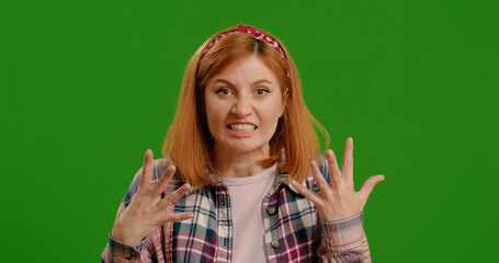 Angry Girl Swear at Camera, isolated on green background. Woman Wearing in Blue Shirt Feeling...