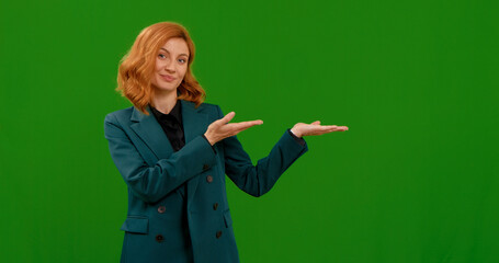 Female hand sign left in approval of something good on chroma key background. Woman looking into the camera, smiling showing to the left gestures with hands on green chroma key screen.