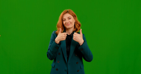 Caucasian woman shows double thumbs up to the camera and nods with a smile on green screen background. Female seller approving a good product. Gesture concept.