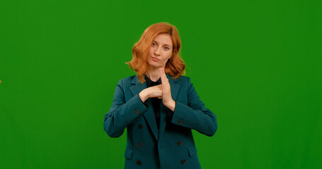 A woman is showing different gestures while standing in front of a bright green background. She appears confident and engaged, showcasing expressive hand movements.