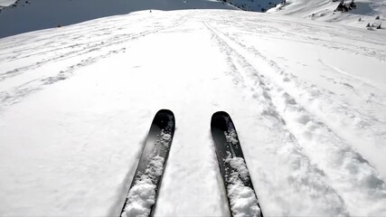 Skis moving across a snow covered mountain slope as seen from a first-person perspective, winter sport recreation footage.