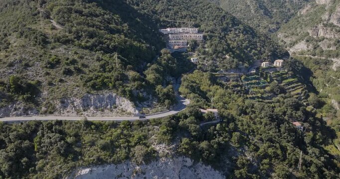 Aerial view of buildings nestled on a steep hillside, with a road winding through the lush greenery, creating a scenic contrast, Erchie, Amalfi Coast, Italy.