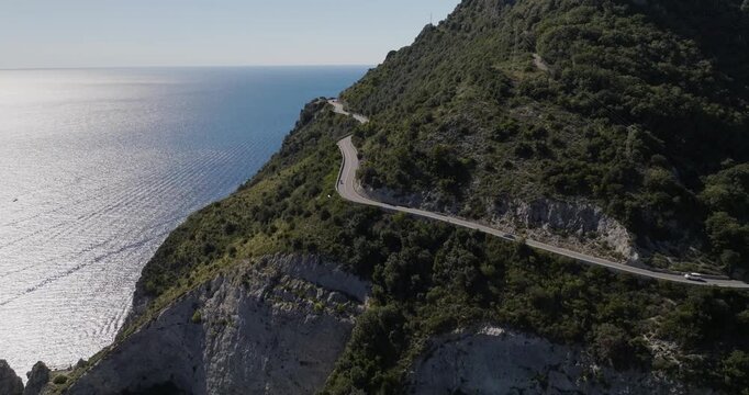 Aerial view of a winding coastal road hugging the rugged cliffs near the tranquil, blue sea waters, Erchie, Amalfi Coast, Italy.