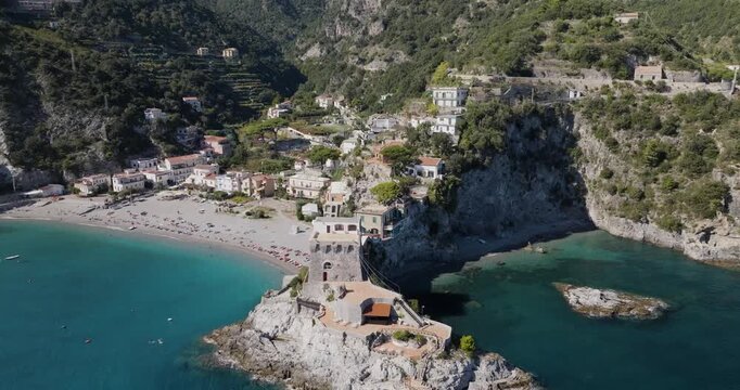 Aerial view of Torre La Guardiola on a rocky outcrop, embraced by the turquoise sea and a sandy beach, Erchie, Amalfi Coast, Italy.