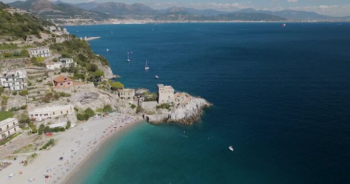 Aerial view of the beach and medieval tower in Erchie, where the turquoise sea meets the sandy beach and historic buildings, Erchie, Amalfi Coast, Italy.