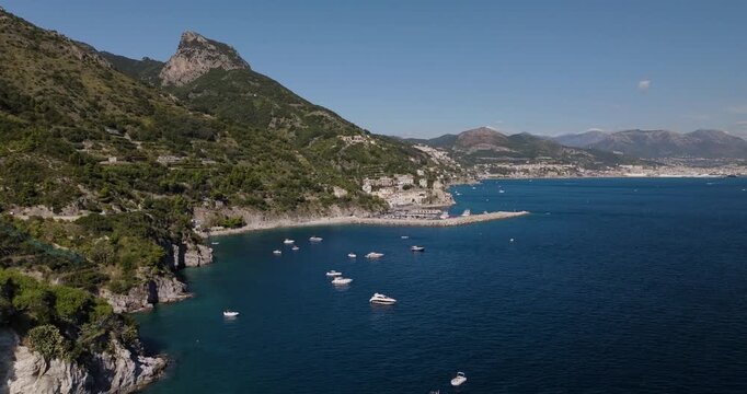 Aerial view of the Erchie coastline, where azure waters meet the rugged, green landscape dotted with boats under a clear sky, Erchie, Amalfi Coast, Italy.