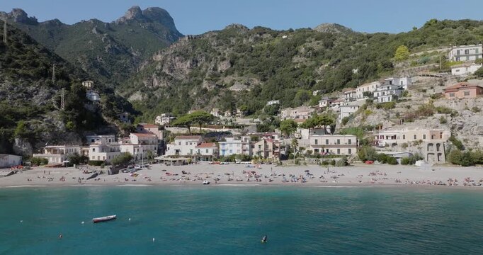 Aerial view of the sun-kissed Erchie beach, where turquoise waters meet the sandy shore, contrasting with the green hills, Erchie, Amalfi Coast, Italy.
