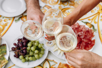 Group of friends toasting with wine glasses over a beautifully arranged table filled with fruits and gourmet delicacies, celebrating togetherness and joy