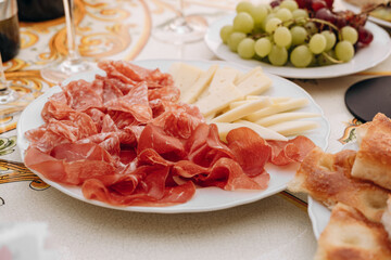 Assorted cured meats and cheeses arranged on a white plate