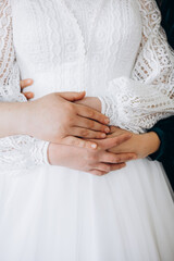 Tender moment — couple’s hands on the bride’s waist in a white lace dress. A symbol of love, care, and unity, reflecting purity and harmony of the wedding day.
