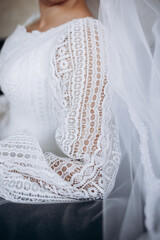 Close-up of a wedding dress with a luxurious lace sleeve and veil. The delicate fabric texture conveys elegance, sophistication, and the romantic atmosphere of a special day.
