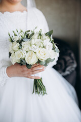 Bride holding a wedding bouquet of white roses and greenery. A tender and elegant image symbolizing purity, harmony, and the beginning of a new happy life.