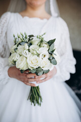 Bride holding a wedding bouquet of white roses and greenery. A tender and elegant image symbolizing purity, harmony, and the beginning of a new happy life.