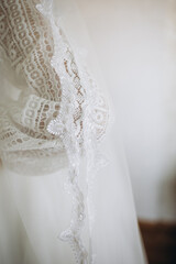 Close-up of a wedding dress with a luxurious lace sleeve and veil. The delicate fabric texture conveys elegance, sophistication, and the romantic atmosphere of a special day.
