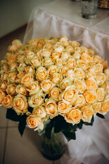 A large bouquet of delicate peach roses in a glass vase. The floral arrangement symbolizes tenderness, gratitude, and warmth — a perfect gift for weddings or special occasions.