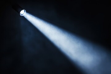 Concentrated spotlight shines brightly in the dark studio illuminating the scene and creating a mysterious atmosphere.