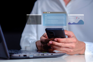 Person Using Smartphone while Working on Laptop with Floating Data Screens Representing Technology and Modern Communication in a Professional Setting