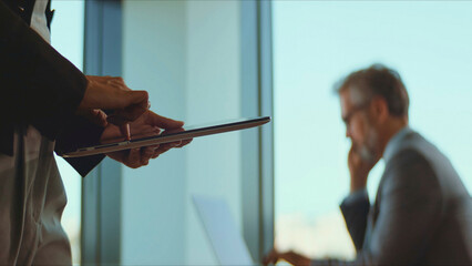 Business colleagues working together, interacting with a digital tablet, sharing information, and discussing project details in a modern corporate office environment with a professional atmosphere