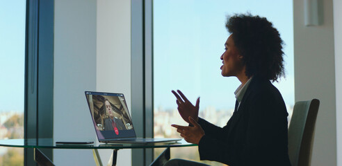 Professional black woman having an important video call discussion on a laptop with a colleague,...