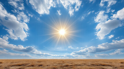 Bright sun shining in clear blue sky with fluffy clouds over golden grassland