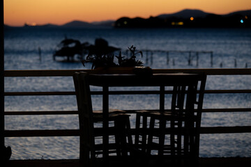 Table and chairs by the sea at sunset with calm evening light